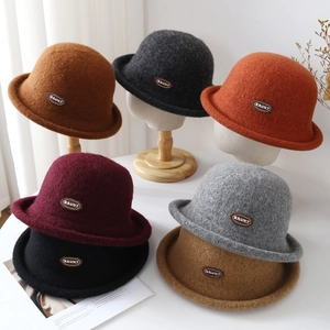 Detail view of multicolored wool cloche hats with a branded logo and stylish curled edges