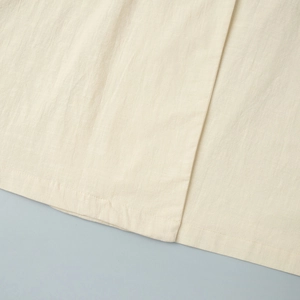 Close-up of beige cotton-linen fabric texture with precise stitching and hem details