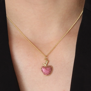 Elegant gold apple pendant necklace with purple crystals worn on a model neckline