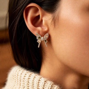 Detailed close-up of bow earrings with sparkling zircons and green gemstones