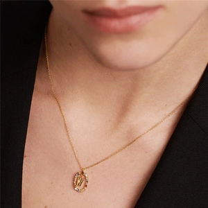 Detailed close-up of a golden W letter necklace with colorful zircon stones on a model