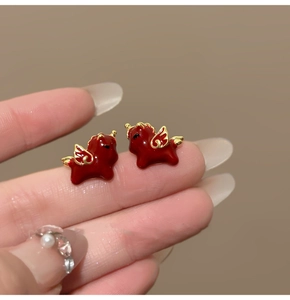 Macro detail of red enamel horse earrings with 18k gold plating and small wings