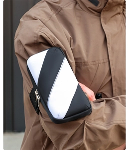 Close-up of black and white striped sports arm bag with zipper and elastic strap on arm