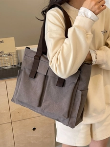 Borsa tote in tela grigia con manici marroni e tasche frontali sulla modella