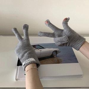 Close-up of grey knit gloves with touchscreen finger openings and white wrist labels