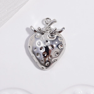 Macro shot of silver strawberry metal pendant with textured surface on white background