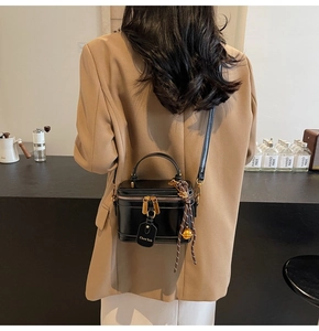Detail of black box bucket bag with gold zippers and brand tag in a cafe setting