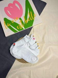 Detailed view of white cotton ankle socks with colorful embroidery on a straw mat