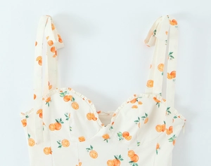 Detail of lace trim neckline and orange fruit print on white woven summer dress