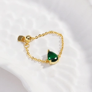 Détail d'une bague ajustable plaquée or 18k avec une pierre verte de forme poire