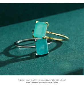 Close-up of rectangle green gemstone rings with four-prong setting in gold and silver finish