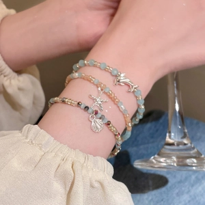 Detailansicht der geschichteten Kristallperlenarmbänder mit Delphin- und Seesternanhängern