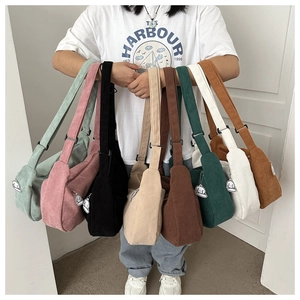 Multiple colors of corduroy crossbody small square bags shown by model in a fan layout