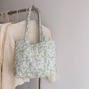 Detail of floral quilted cotton tote bag featuring French label on a hanging display