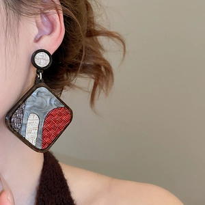 Macro side view of vintage geometric diamond earrings featuring woven textures on model