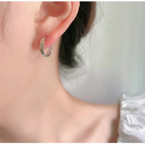 Detailed view of silver hoop earrings on model featuring a polished twisted texture
