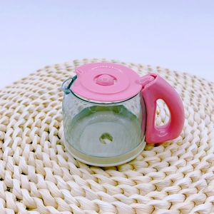 Detailed close-up of a toy coffee pot with pink lid on a woven mat for kids play kitchen