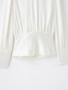 Détail du chemisier en satin blanc avec plis à la taille et fermeture éclair invisible