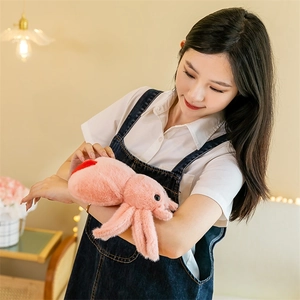 Close-up of a soft pink plush spider toy held by a model in a warm indoor setting