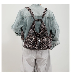 Detailed back view of leopard print backpack with multiple zip pockets and metal ring accents