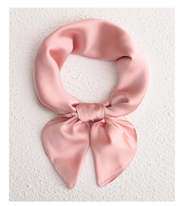 Detailed view of pink silk scarf tied in a bow showing soft texture and glossy finish