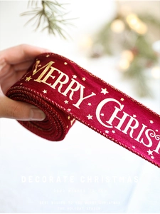 Detail of red velvet Christmas ribbon with gold Merry Christmas print and star patterns