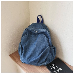 Detailed close-up of a blue denim backpack displayed on a rustic wooden shelf