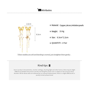 Detailed view of tassel earrings with yellow butterfly charms and white pearls