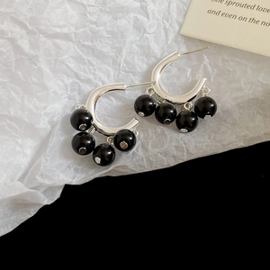 Detailed close-up of retro C-shaped silver earrings with dangling black glossy beads
