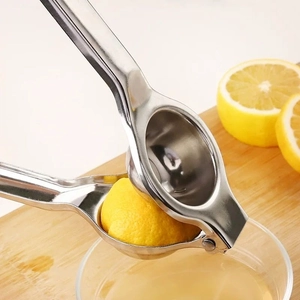 Manual stainless steel lemon squeezer pressing fresh juice into a glass bowl