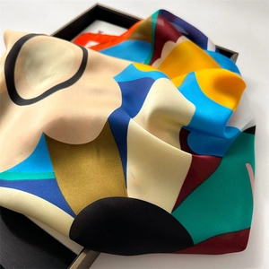 Detail view of the colorful floral geometric silk scarf displayed in a black tray