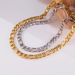 Detailed view of polished gold and silver Figaro chain necklaces on a white surface