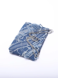 Close-up of distressed blue denim bag with frayed tassel details and silver metal chain