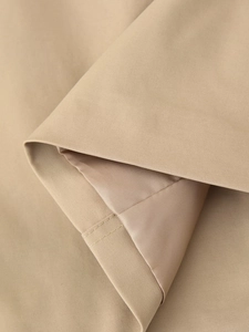 Close-up of khaki trench coat showing fine twill fabric texture and smooth inner lining