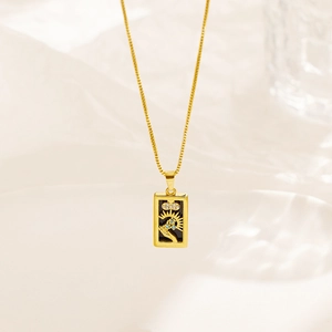 Macro view of gold tarot card pendant featuring sunburst rays and tiny zircon accents