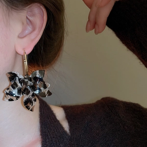 Close-up of elegant leopard print resin flower C-shaped hoop earrings worn by a model