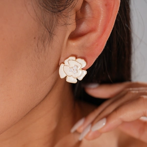 Close-up of a vintage resin flower earring with a pearl center on a female model's ear