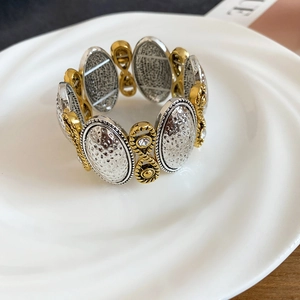 Close-up of gold and silver elastic bracelet with textured plates and zircon stones