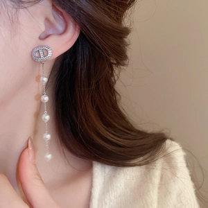 Detail of silver drop earring with tassel pearl and zircon on model in soft light