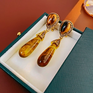 Macro detail of vintage tiger eye teardrop earrings on green leather jewelry box