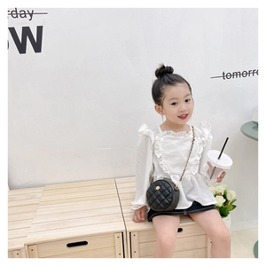 Detail view of child's black quilted round crossbody bag with golden chain and flower buckle