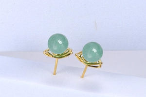 Detailed macro view of green aventurine earrings with gold wire-wrapped weave design