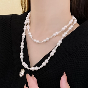 Gros plan d'un collier de perles à double rangée avec différentes tailles sur maille noire