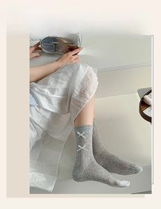 Detail of grey knitted mid-calf socks featuring white bows and fine vertical rib texture