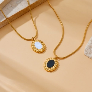 Détail de colliers dorés avec pendentifs géométriques ovales noirs et blancs vintage