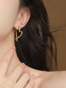 Close-up of a minimalist gold heart-shaped stud earring worn on the ear for women
