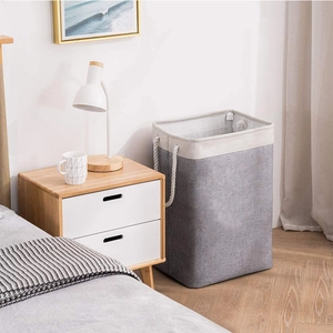 Detailed shot of grey and beige canvas laundry hamper with cotton rope handles in bedroom