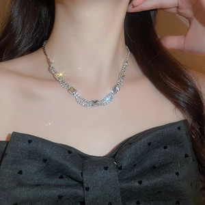 Close-up of a vintage silver necklace with square diamond pendant on a model's neck