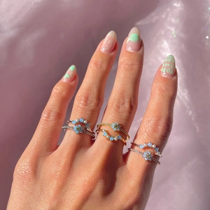 Detailed view of three-tone floral ring set with blue opal stones and pearls on silk