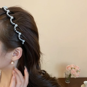 Detail view of wavy pearl headband and matching champagne pearl earring on a model